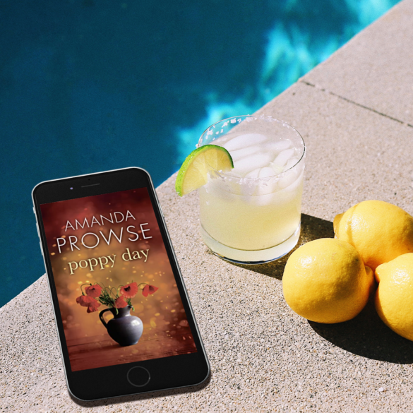 Poppy Day by Amanda Prowse book cover on an iphone next to a pool with a glass of juice and lemons